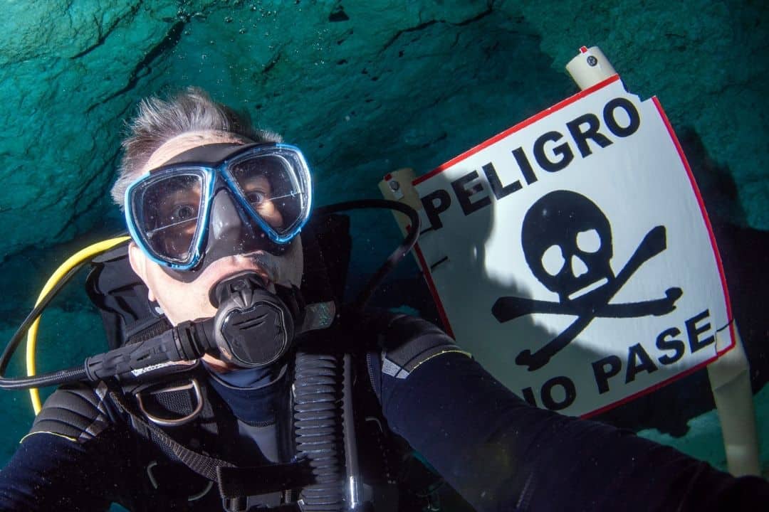 cave diver with a danger warning sign
