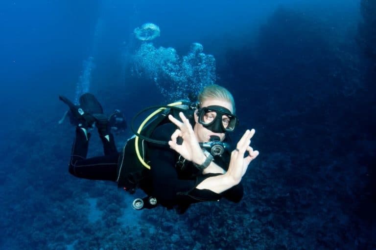 scuba diver making the ok sign while breathing in his regulator